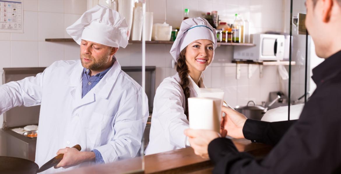 Staff at food business giving takeaway food to customer